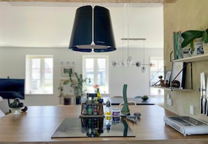 A modern kitchen with a central island, a hanging light fixture, and a laptop on the counter. - House with soul in Klitmøller (Klitmøller)
