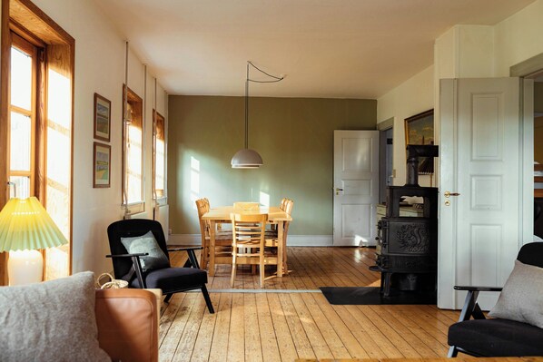 Una habitación con una mesa de comedor, sillas, un sofá, una lámpara y una chimenea.