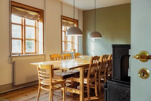 Un comedor con mesa y sillas de madera, una ventana con cortinas y una estufa.
