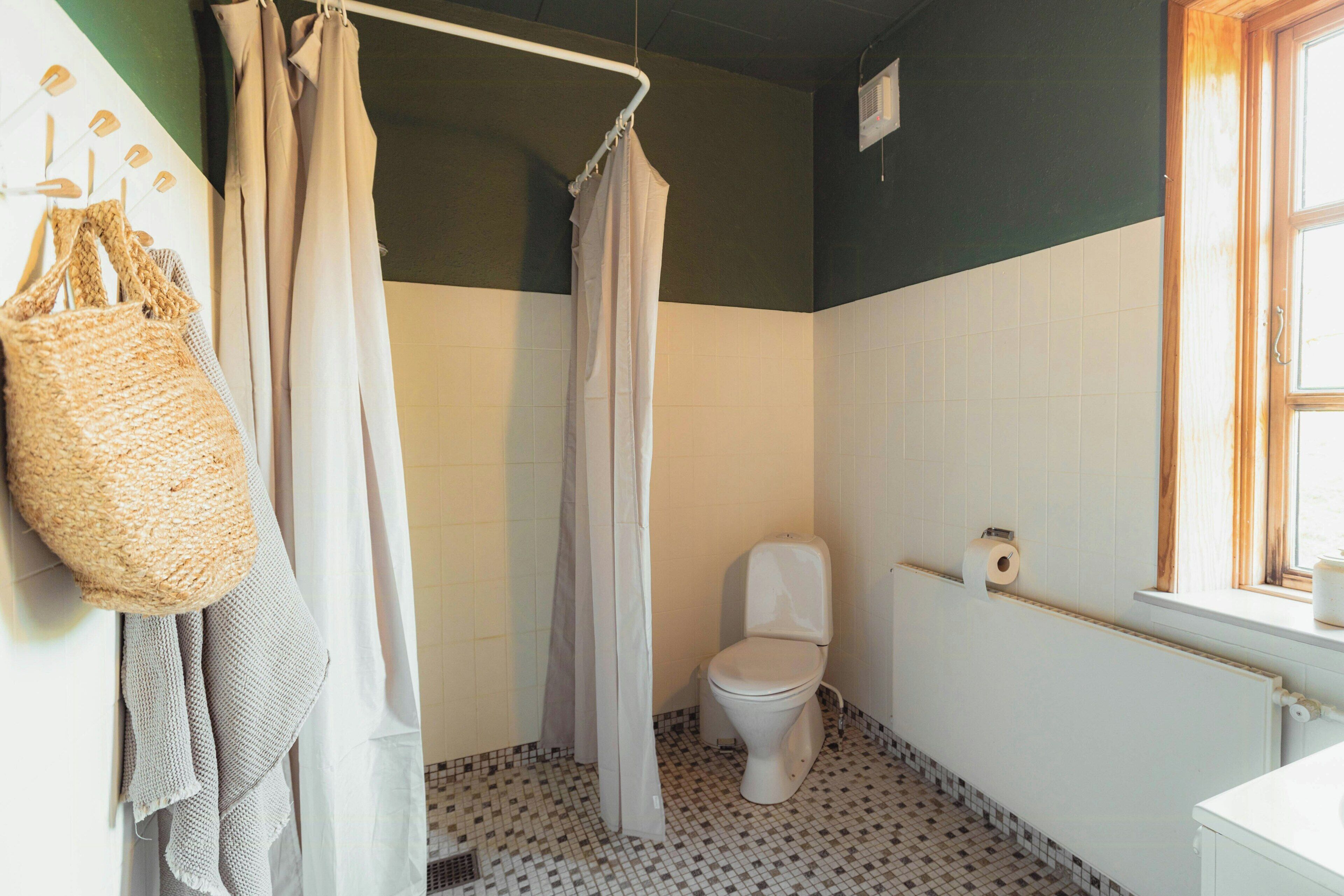 Un baño con inodoro, cortina de ducha y una bolsa colgada.