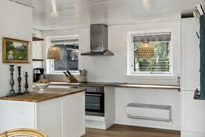 A modern kitchen with white cabinetry, a built-in oven, a window with a view, and pendant lights. - Sea view from cozy home in Vejby (Vejby)