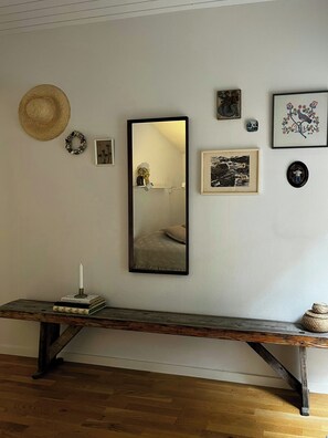 Ein Zimmer mit einer hölzernen Bank, einem Spiegel und verschiedenen gerahmten Kunstwerken an der Wand.