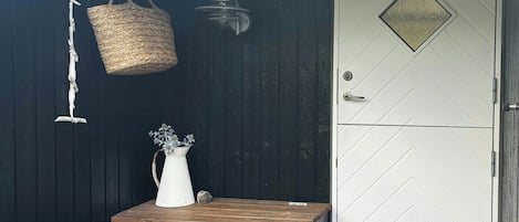 A wooden deck with a white door and a small table with a vase and basket.