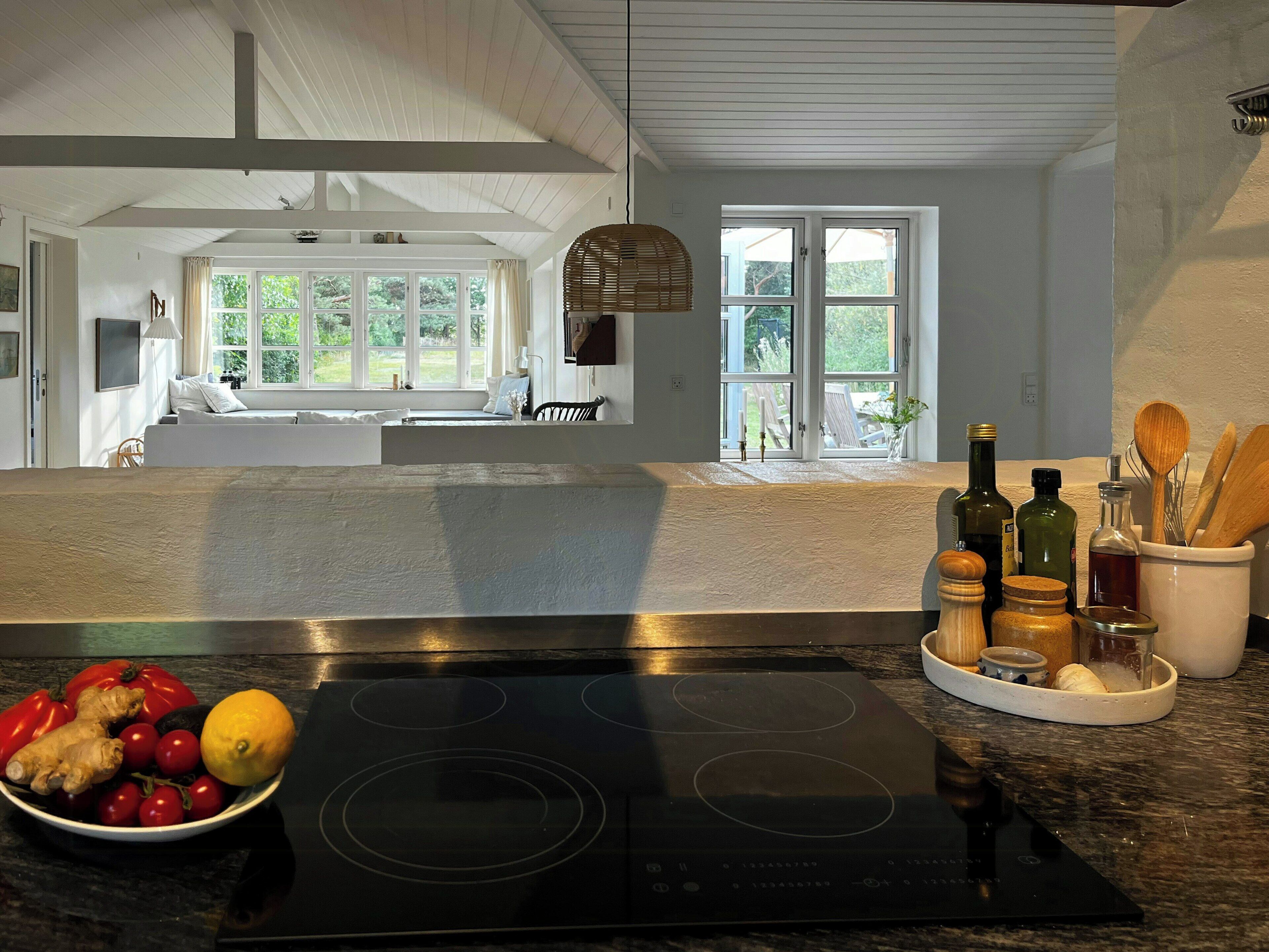 A kitchen with a large island, a bowl of fruit, and various kitchen utensils.
