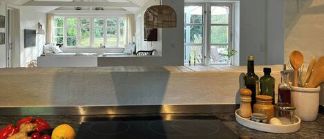 A kitchen with a large island, a bowl of fruit, and various kitchen utensils.