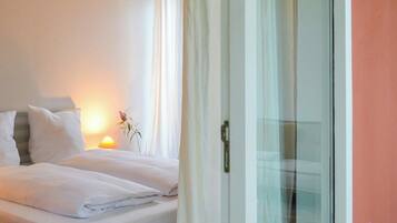 A bedroom with a bed, a nightstand with a lamp, and a sliding glass door leading to a balcony.