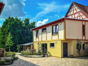 A two-story building with a traditional facade, a stone pathway, and a garden area. - Franconian farm house with sauna in Haßberge (Hofheim i. Ufr.)