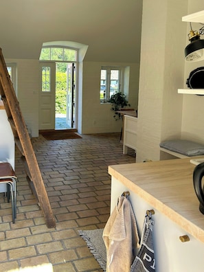 Ein Zimmer mit Backsteinboden, einem Holzstuhl, einem Schreibtisch und einer an der Wand angelehnten Leiter.