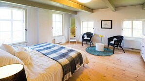 Ein Schlafzimmer mit einem Bett, zwei Stühlen, einem runden Tisch und einem Fenster.