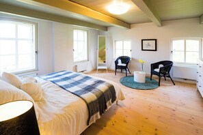 Ein Schlafzimmer mit einem Bett, zwei Stühlen, einem runden Tisch und einem Fenster.
