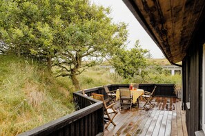 Eine Holzterrasse mit Gartenmöbeln, einem Tisch und Stühlen.