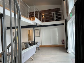 Un interior de varios niveles con una escalera, un comedor y una puerta con extintor.