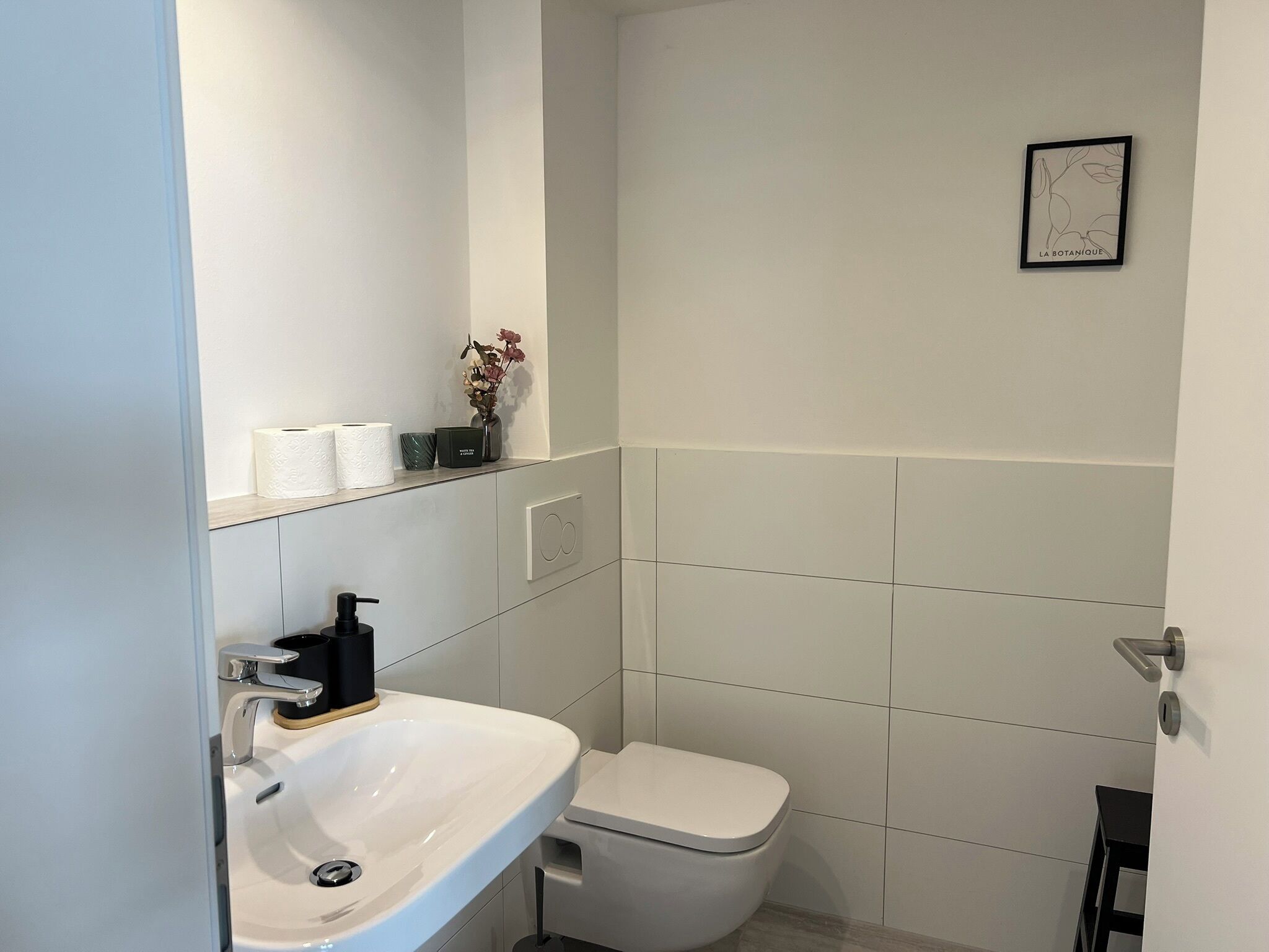 Un bagno moderno con lavandino, water e un piccolo ripiano con articoli da toilette.