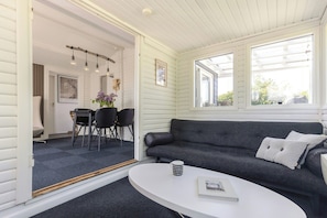Ein modernes Interieur mit einem dunkelgrauen Sofa, einem weißen Couchtisch und einem Essbereich mit Stühlen und einem Tisch.