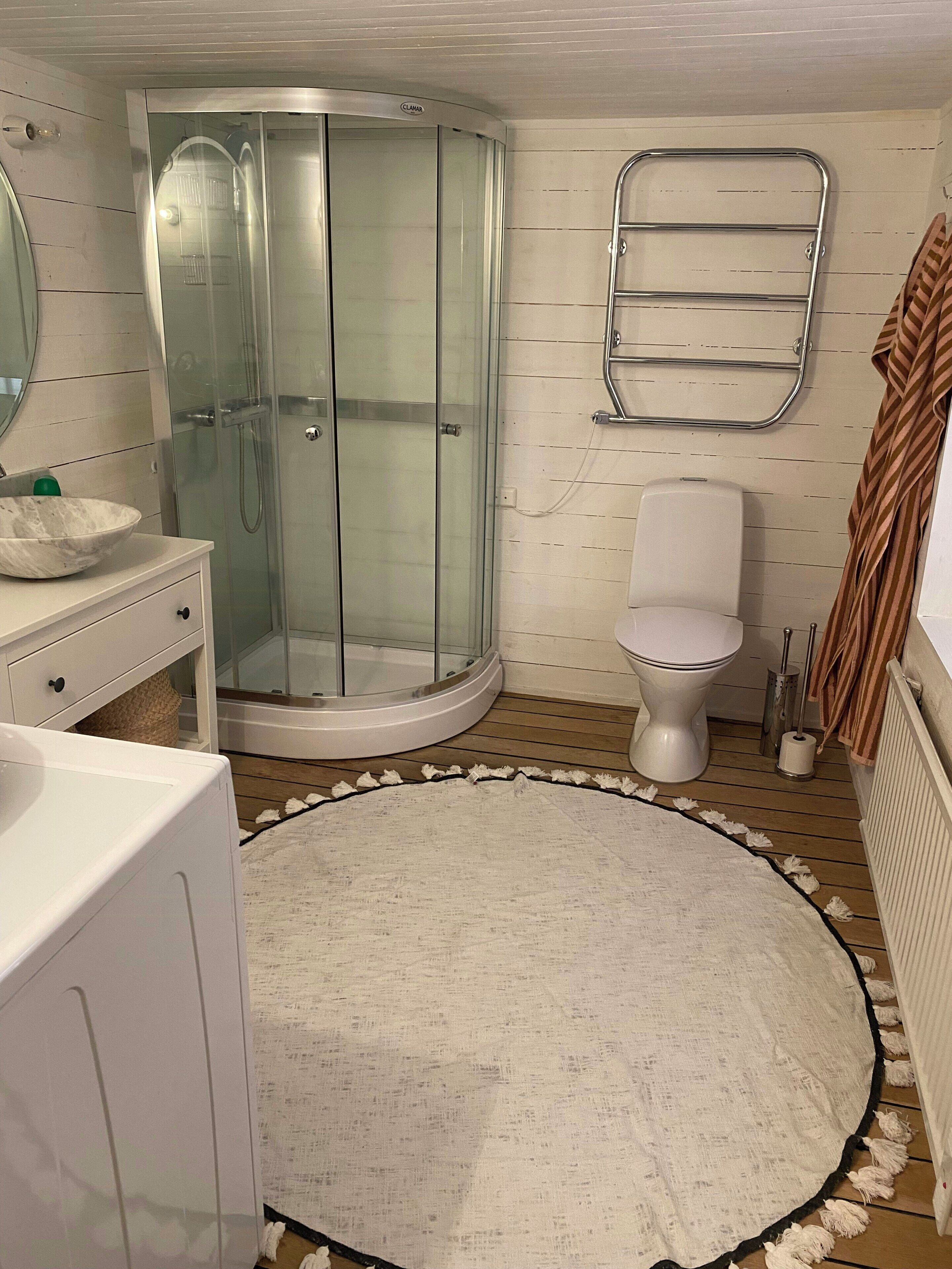 Une salle de bain avec une douche à parois de verre, des toilettes, un lavabo avec un receveur en marbre et un porte-serviettes.