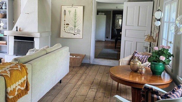 Una sala acogedora con un sofá, una mesa de comedor de madera y una silla blanca.
