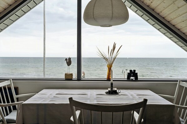 A table with a white tablecloth, a vase with dried reeds, and a candle on a windowsill. - Home with views and walking distance to nature (Nyborg)