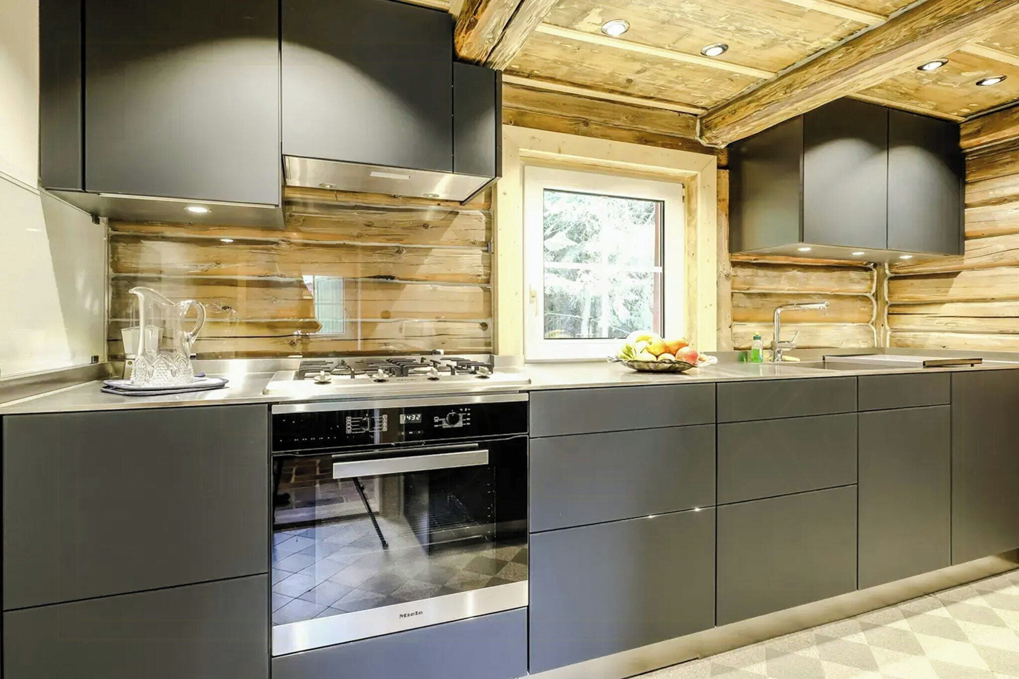 A modern kitchen with stainless steel appliances, wooden paneling, and a window providing natural light.