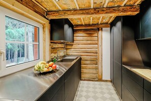 Eine Küche mit Holzbalkendecke, einem Fenster und einer Obstschale auf der Arbeitsfläche.