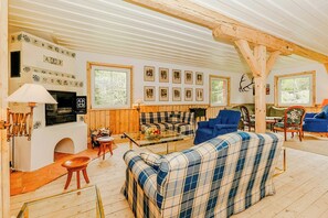 Ein gemütliches Wohnzimmer mit Kamin, Karo-Möbeln und gerahmten Bildern an der Wand.