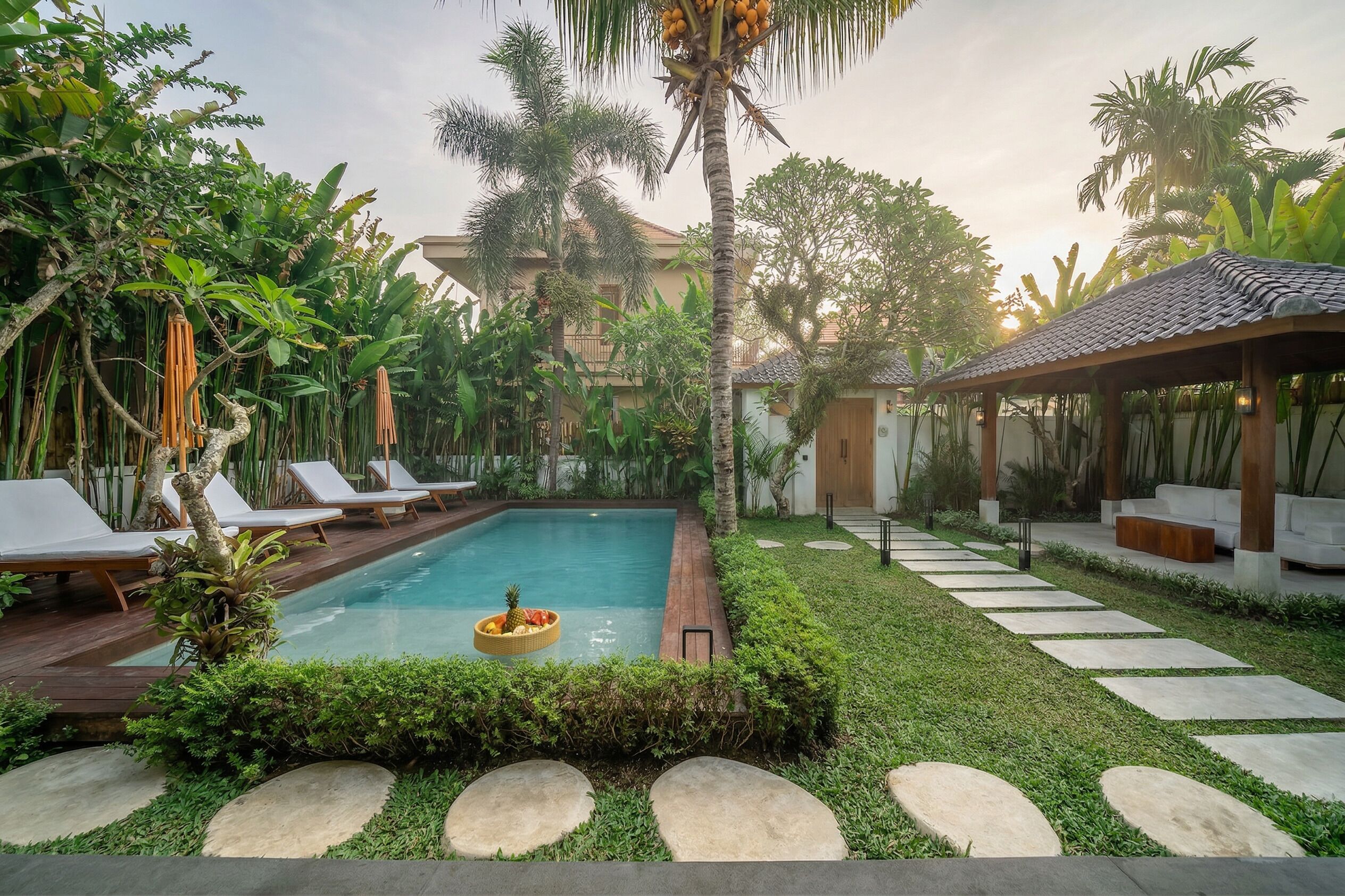 A pool area with lounge chairs, a small pool, and a covered seating area.