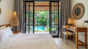 Quarto com cama, escrivaninha, luminária, espelho e vista para uma piscina e jardim.