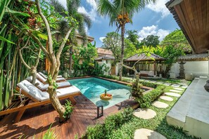Une piscine avec des chaises longues, un jardin agrémenté de pas japonais et un belvédère.