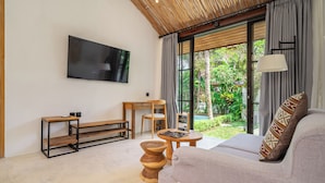 Uma sala de estar moderna com uma televisão de tela plana, um sofá, uma mesa de centro de madeira e um banco.