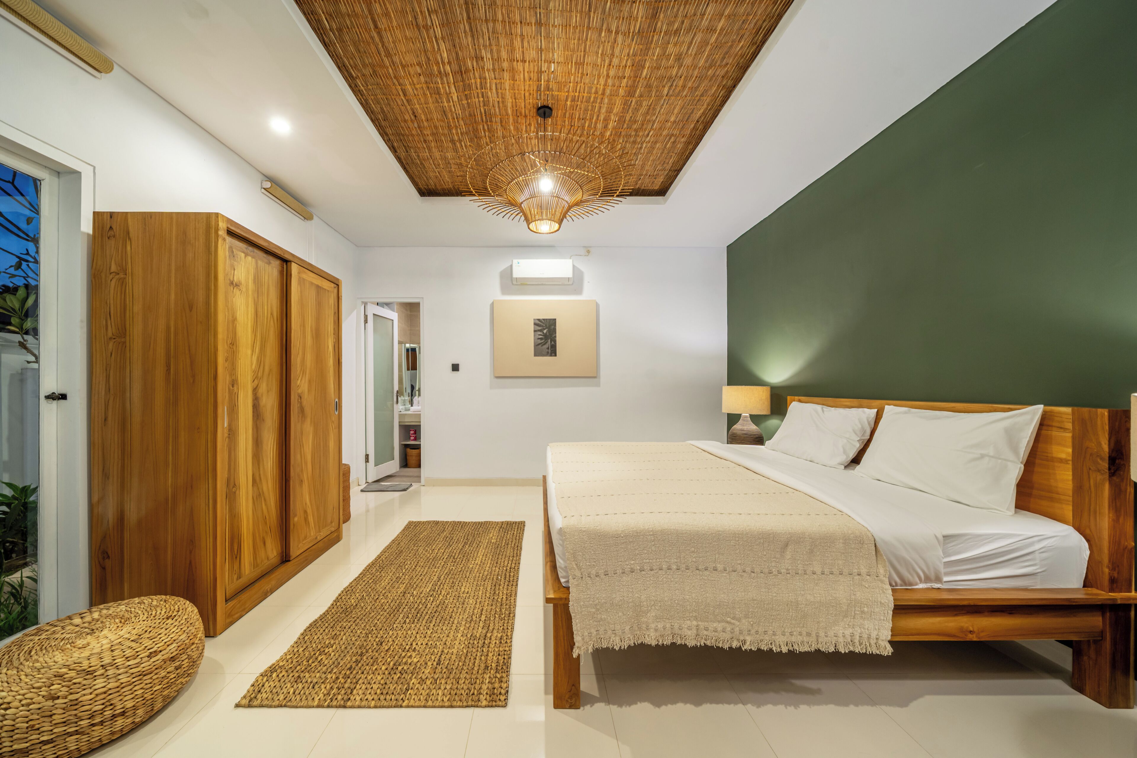 Een slaapkamer met een bed, een houten kledingkast, een geweven vloerkleed en een plafondventilator.