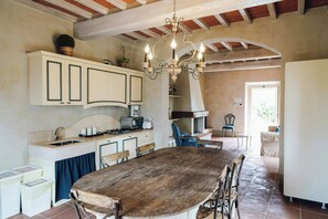 A kitchen with a wooden table, white cabinets, and a hanging chandelier. - Farm apartment with pool near Florence (Reggello)