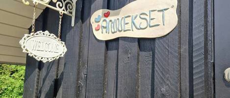 Een houten muur met twee borden, waarvan het ene 'WELCOME' en het andere 'ANUKESET' vermeldt.
