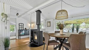 Un intérieur moderne avec une cheminée centrale, une table à manger en bois et des chaises.