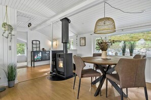 Ein modernes Interieur mit einem zentralen Kamin, einem Holzes Esstisch und Stühlen.