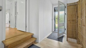 Un intérieur moderne avec un escalier en bois, une porte vitrée donnant sur l’extérieur et un paravent en bambou.
