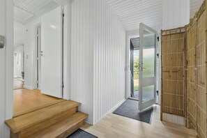 Ein modernes Interieur mit einer Holztreppe, einer Glastür zum Außenbereich und einem Bambusvorhang.