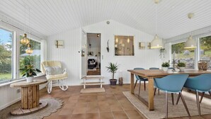 Une pièce spacieuse avec une table à manger en bois, des chaises bleues, un fauteuil à bascule et une plante en pot.