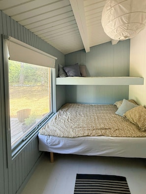 A bedroom with a bunk bed, a window with blinds, a hanging light fixture, and a view of the outdoors. - Wooden cottage near the beach in Odsherred (Asnæs)