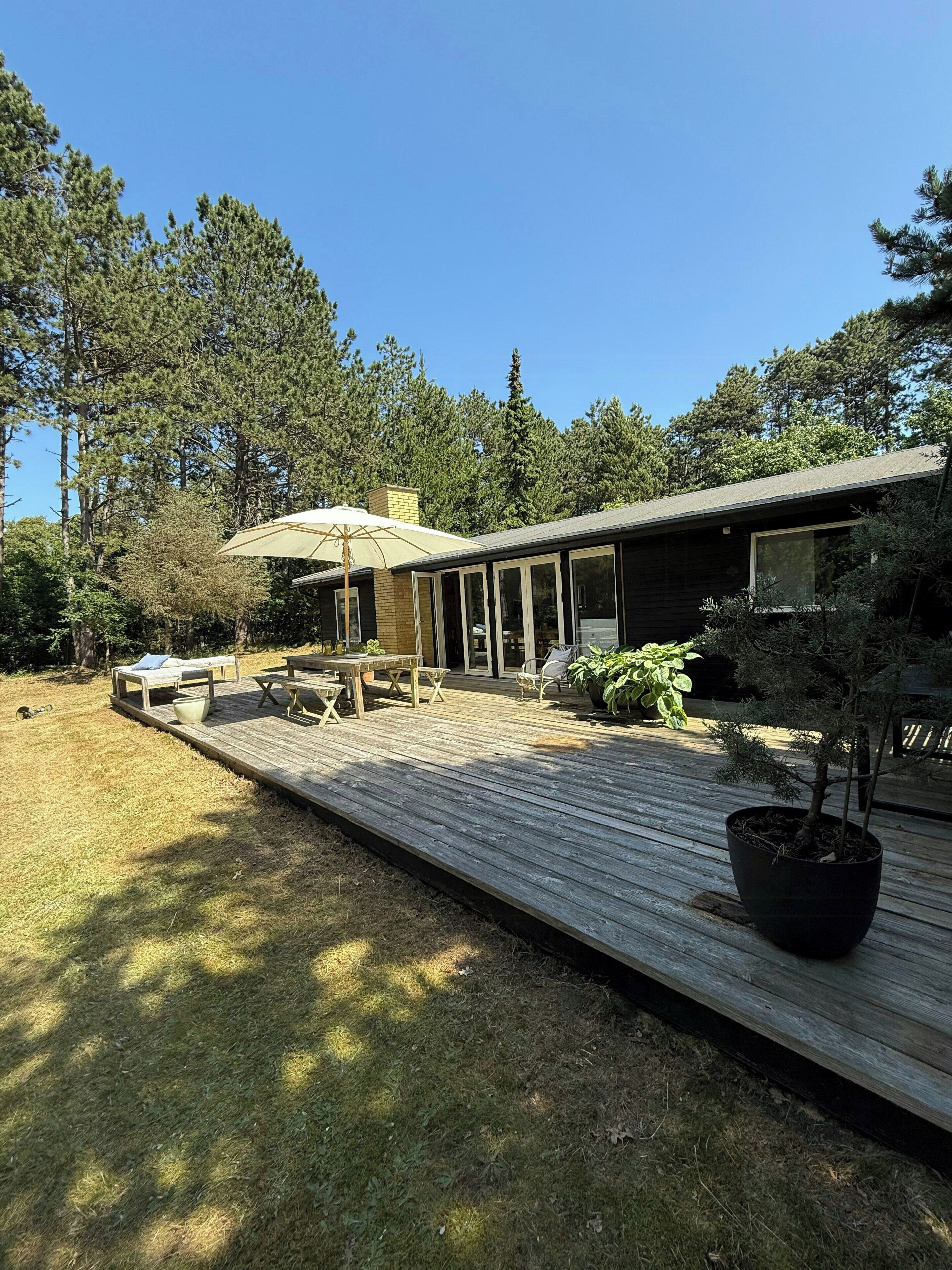 A modern house with a deck, outdoor furniture, and a potted plant.