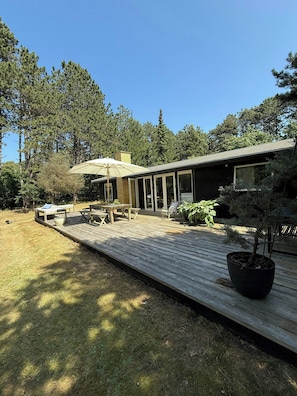 A modern house with a deck, outdoor furniture, and a potted plant. - Wooden cottage near the beach in Odsherred (Asnæs)