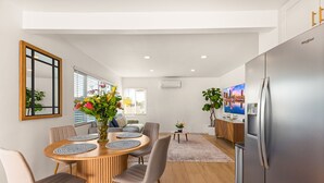 A modern kitchen with a stainless steel refrigerator, wooden dining table with chairs, and a TV on the wall. - Stylish North Park Escape - Private Patio (San Diego)