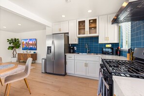 Eine moderne Küche mit weißen Schränken, einem Edelstahl-Kühlschrank, einem Gasherd und einer blauen Küchenzeile.