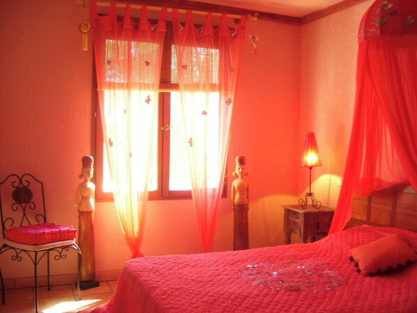 A bedroom with a bed, a nightstand, a chair, and two decorative statues. - Authentic villa in the Var countryside (Les Arcs)