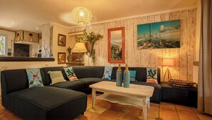 Ein Wohnzimmer mit einem Ecksofa, einem Couchtisch, einem Kamin, einem Gemälde und einer Lampe.