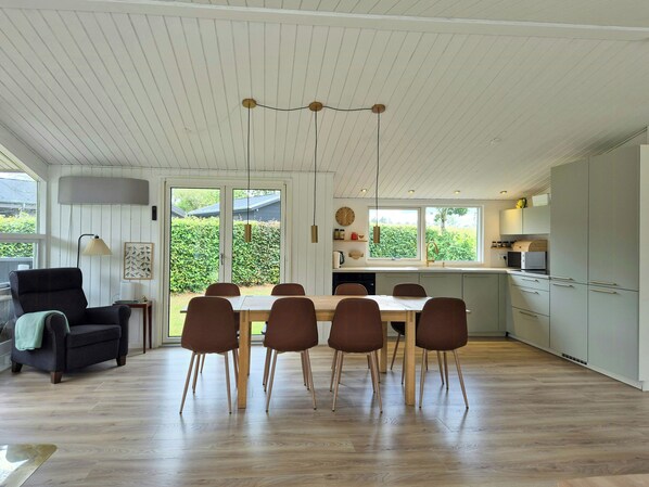 A modern kitchen with a dining area, wooden flooring, and large windows. - Summer house with big canoo near Sminge Lake (Silkeborg)