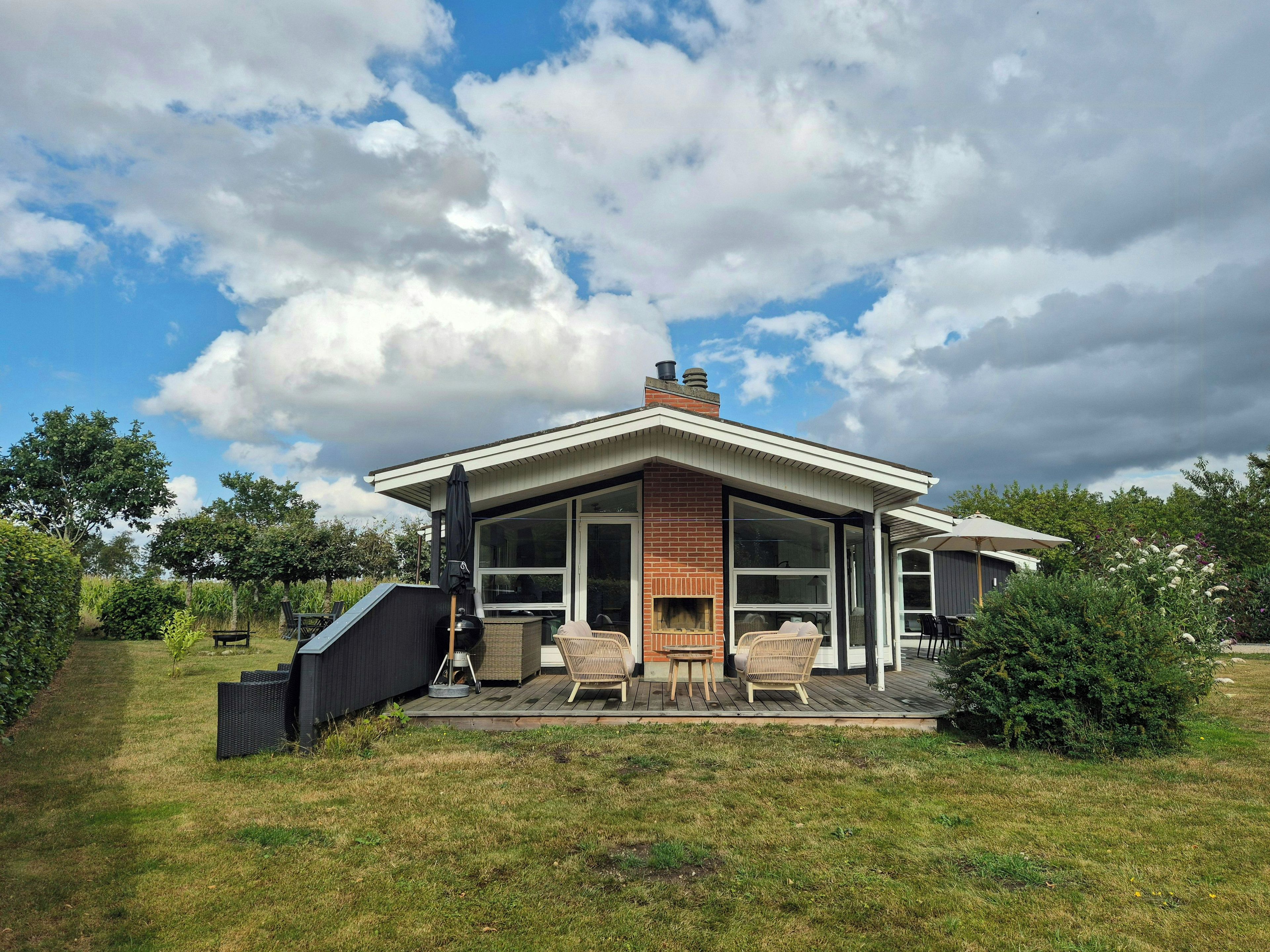 Una casa moderna con un patio, mobiliario exterior y una chimenea.
