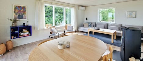 Un salon moderne avec une table ronde en bois, un canapé et un réfrigérateur noir.
