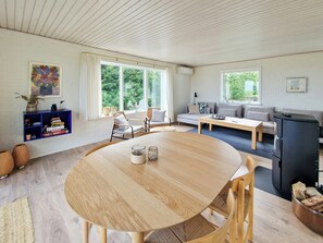 Una sala de estar moderna con una mesa redonda de madera, un sofá y un refrigerador negro.