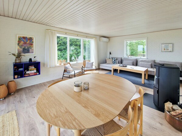 A modern living room with a round wooden table, a sofa, and a black refrigerator. - Beach house with sea view near Hou beach (Hals)