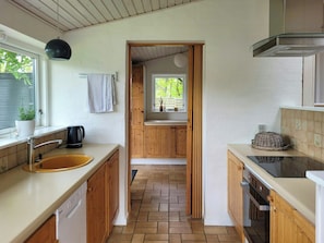 A kitchen with wooden cabinets, a sink, a kettle, and a window with a view of greenery. - Beach house with sea view near Hou beach (Hals)