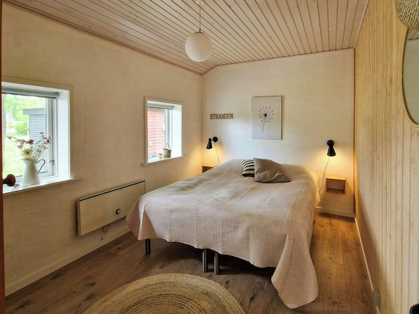 Una camera da letto con un letto, due lampade sui comodini, una finestra vista, un termosifone e un'opera d'arte appesa al muro.